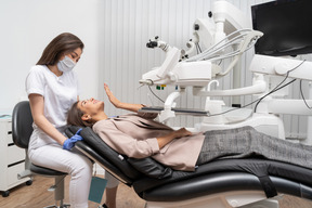 De cuerpo entero de una paciente enviando un beso al aire a su dentista en un gabinete de hospital