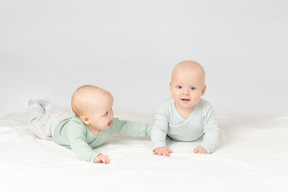 Curiosos bebés gemelos acostados sobre el estómago