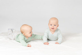 Curious babies twins lying on the stomach