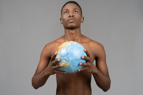 A shirtless young man holding the earth globe