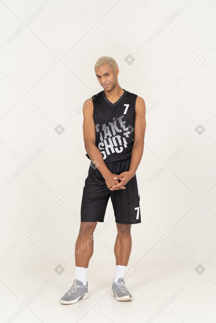 Vista frontale di un timido giovane giocatore di basket maschile che si tiene per mano insieme