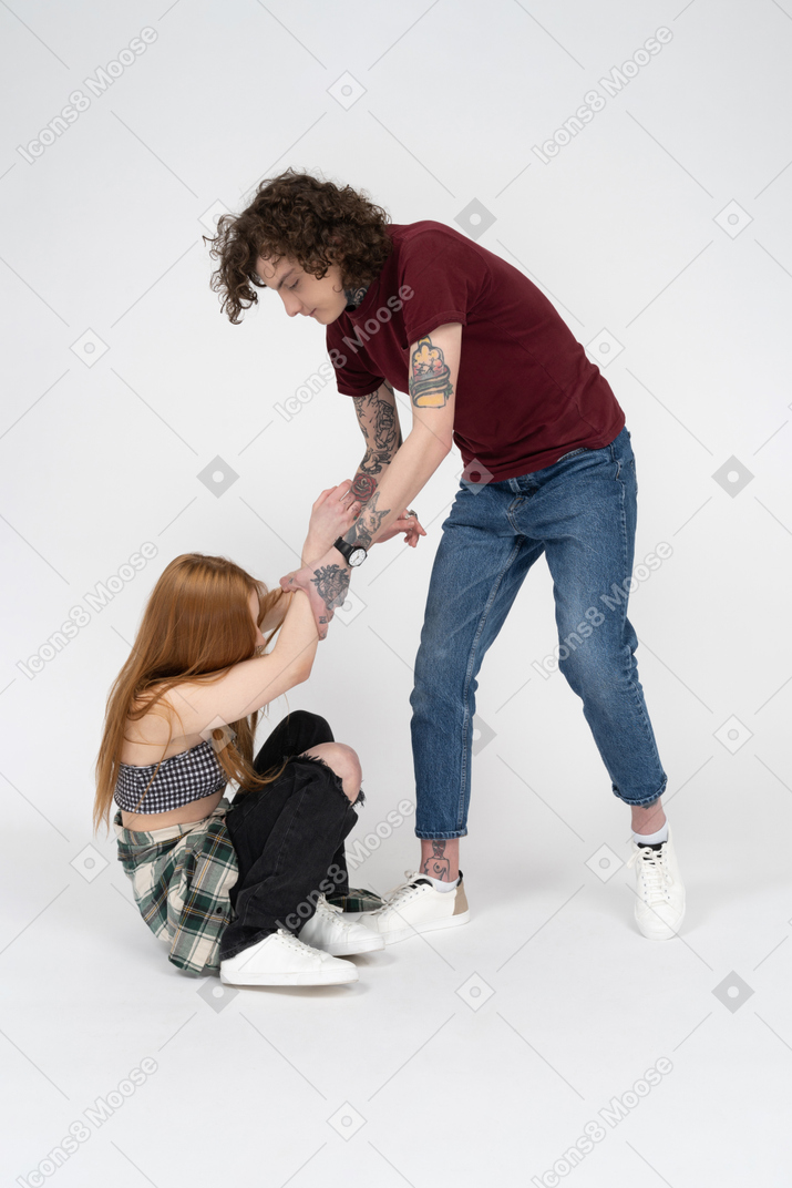Teenage boy helping his girlfriend to get up