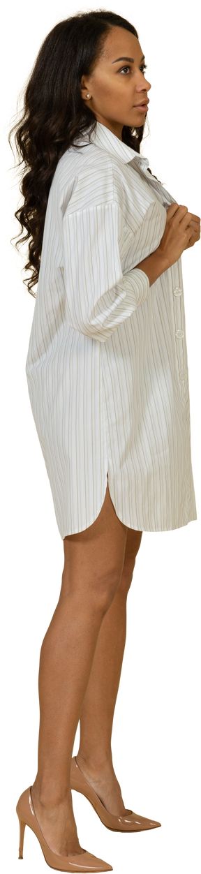Vista lateral de una mujer joven de piel oscura abrochando su vestido blanco