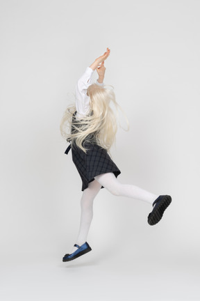 Back view of a schoolgirl jumping with hands up