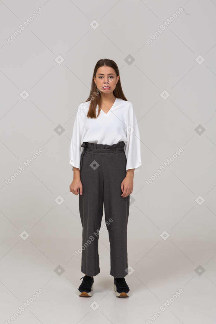 Front view of a young lady in office clothing standing with her lips down