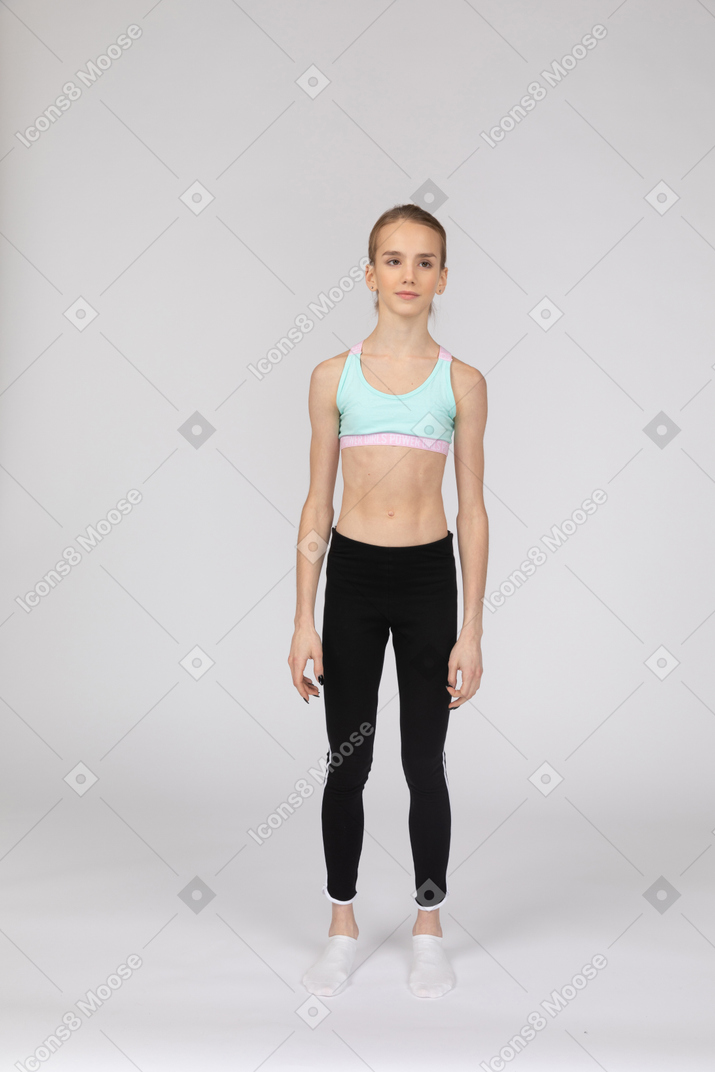 Front view of a teen girl in sportswear standing still and looking aside