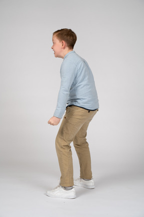 Vista lateral de um menino mostrando o quão forte ele é