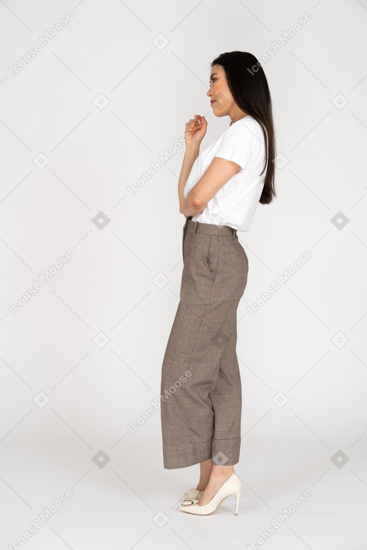 Vista laterale di una giovane donna premurosa in calzoni che attraversano le gambe