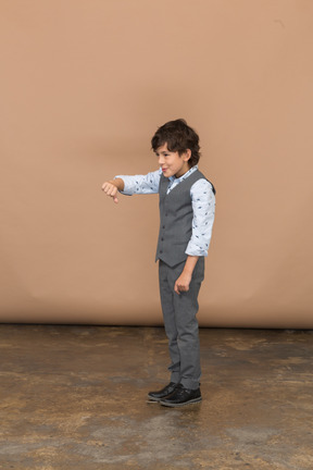 親指を下に示している灰色のスーツを着た少年の側面図