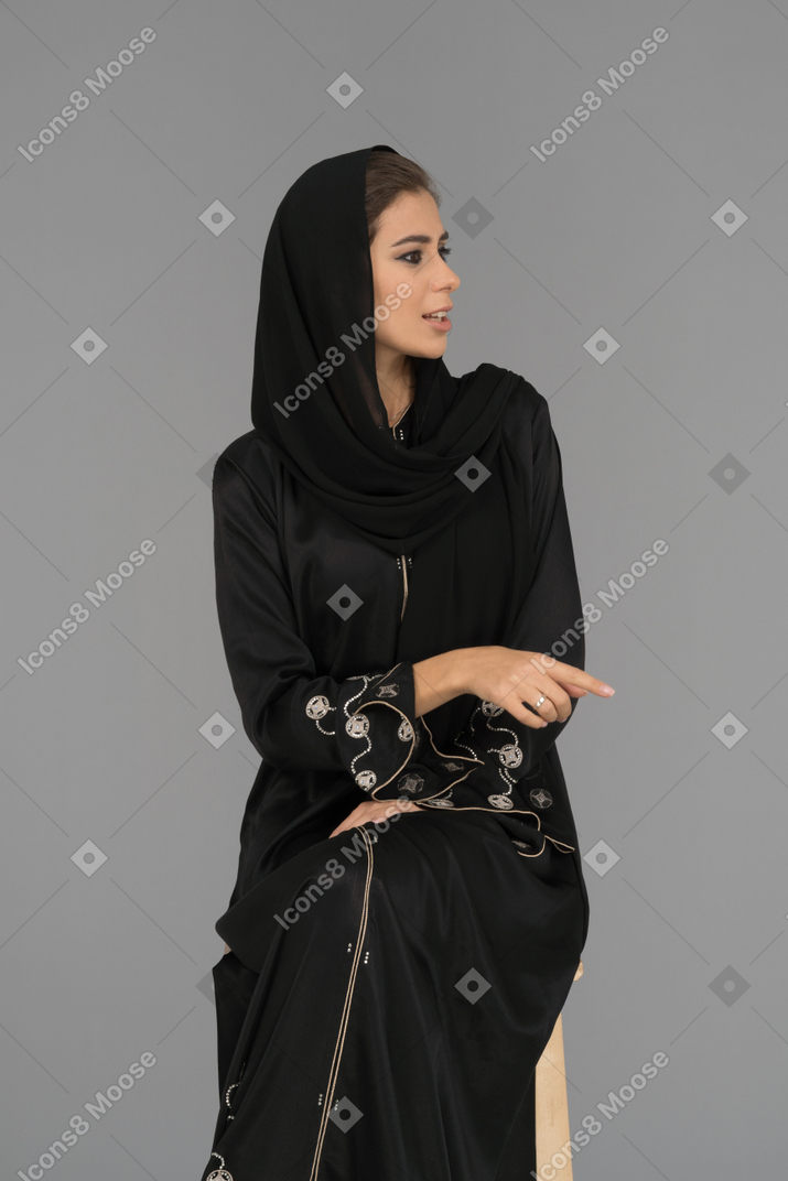 A muslim woman pointing sideways with a finger