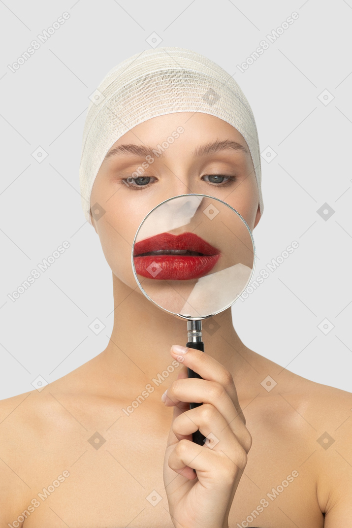 A woman looking at her lips through a magnifying glass