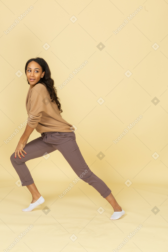 Vista lateral de una mujer joven de piel oscura apoyada en su pierna
