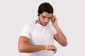 Apuesto deportista ajustando sus auriculares y buscando rastreador de actividad
