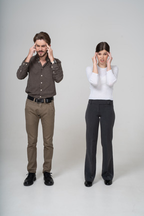 Front view of a shocked young couple in office clothing touching head