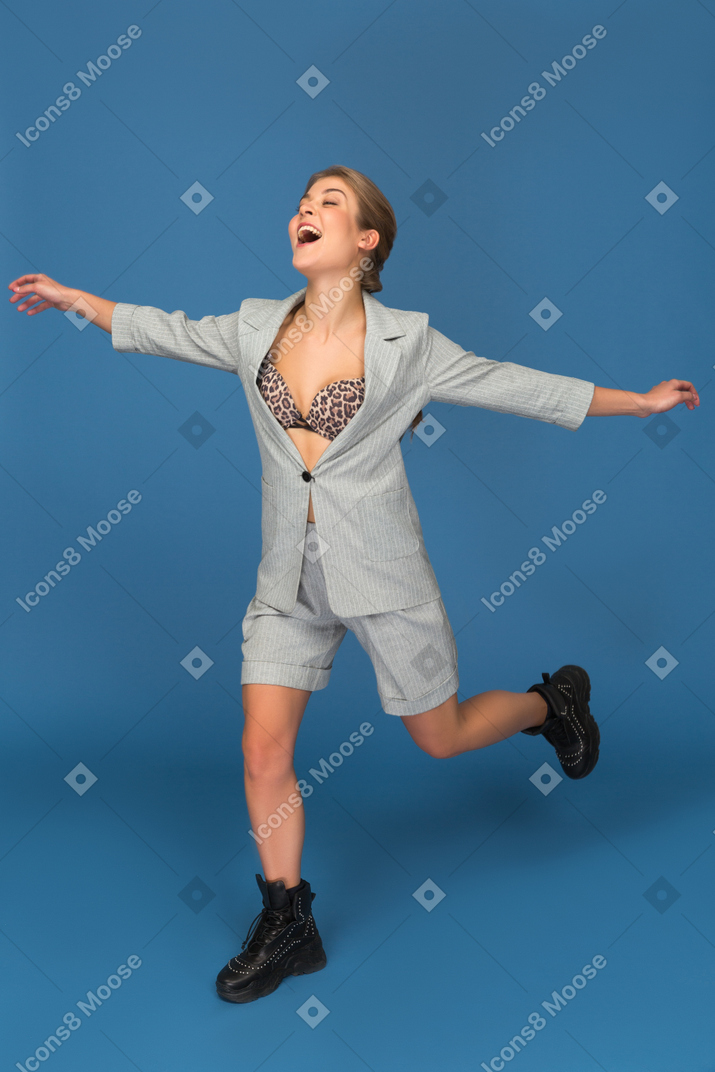 Excited beautiful woman stretching hands and lifting one leg