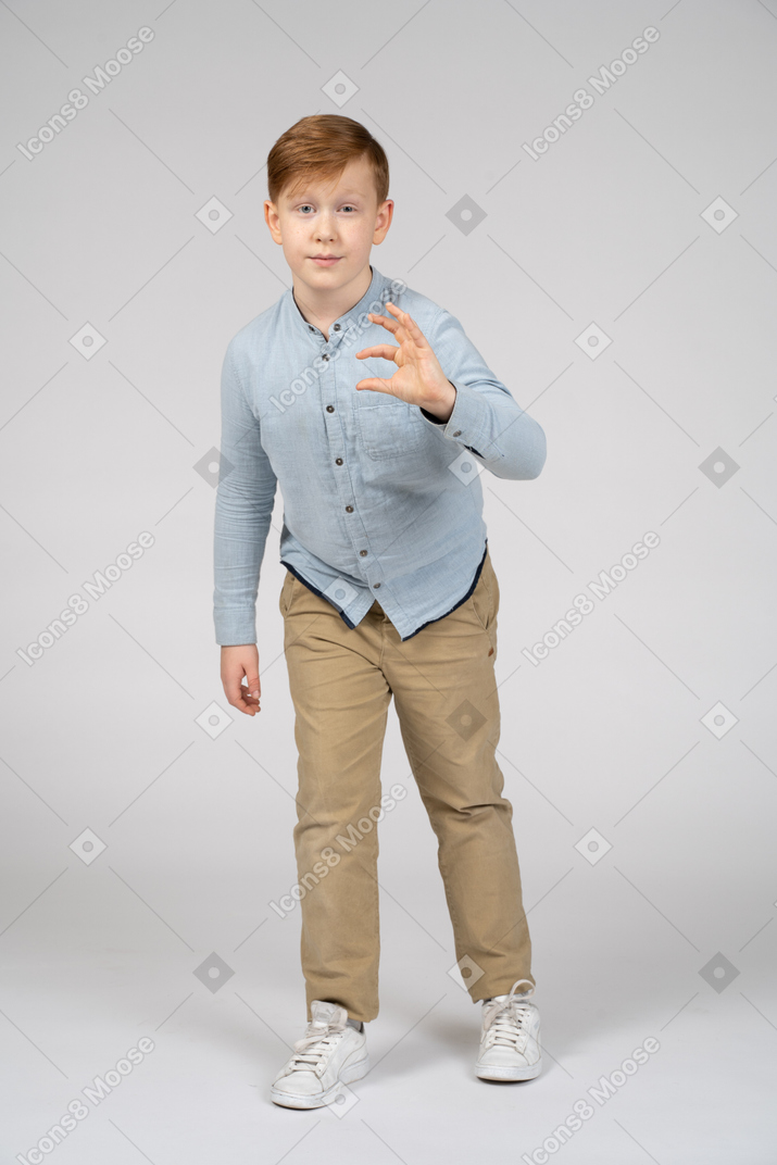 Front view of a cute boy showing size of something and looking at camera
