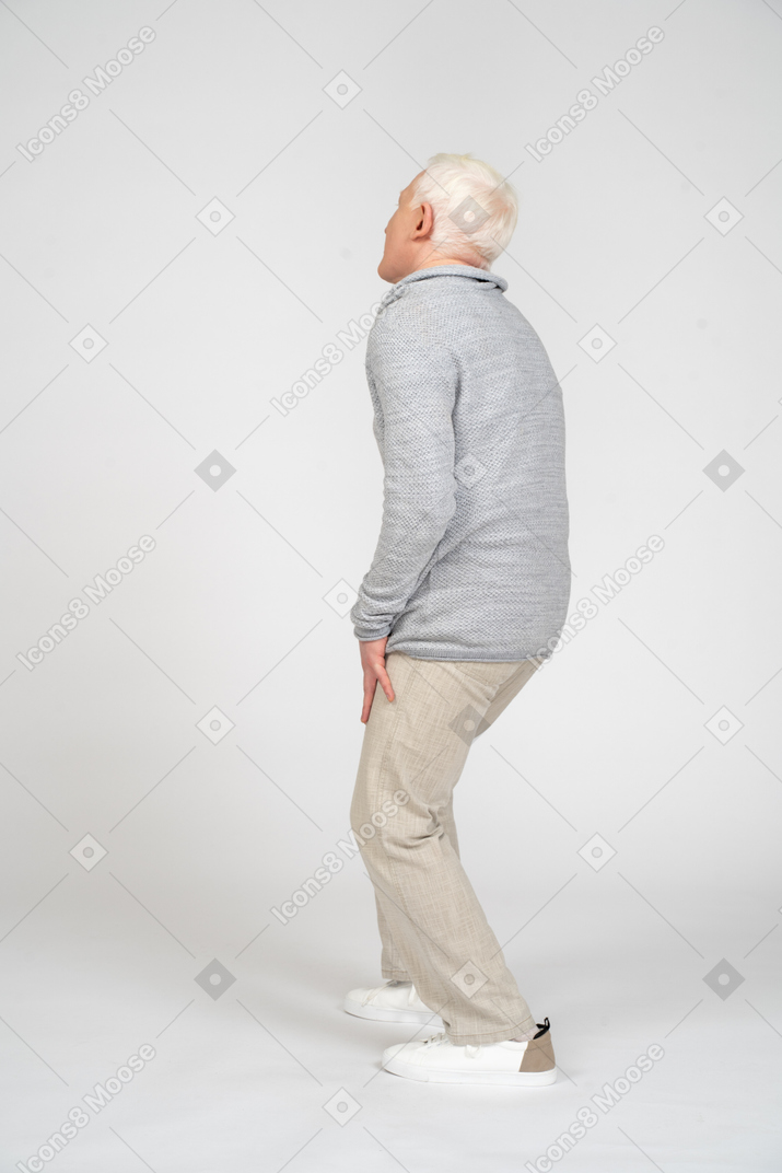 一个男人站立并触摸他的膝盖的侧视图
