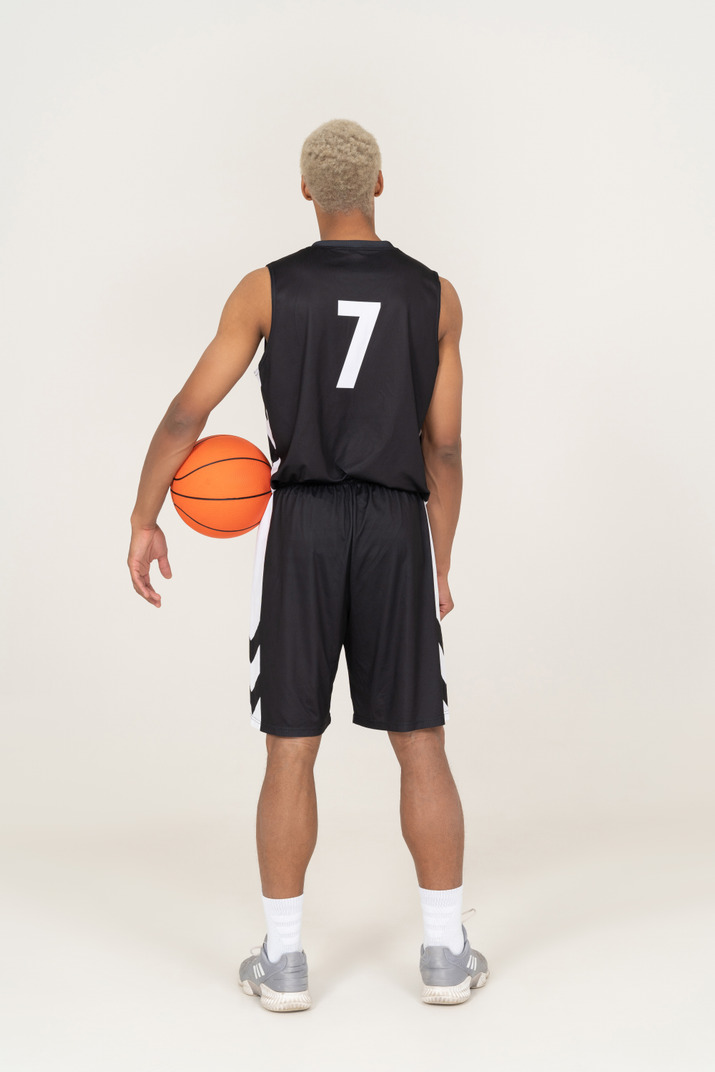 Back view of a young male basketball player holding a ball
