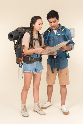 Jovem homem e mulher com mochila enorme olhando atentamente no mapa