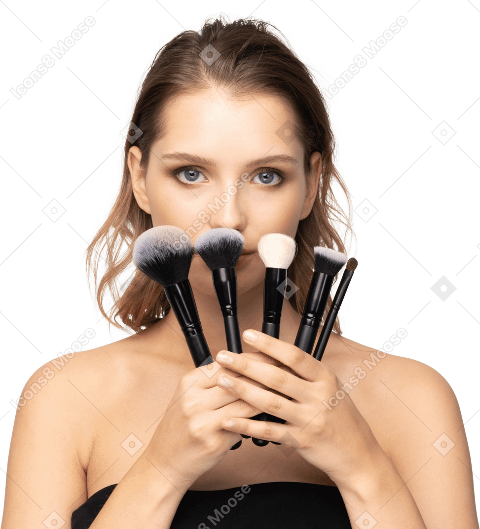 Front view of a sensual young woman holding make-up brushes