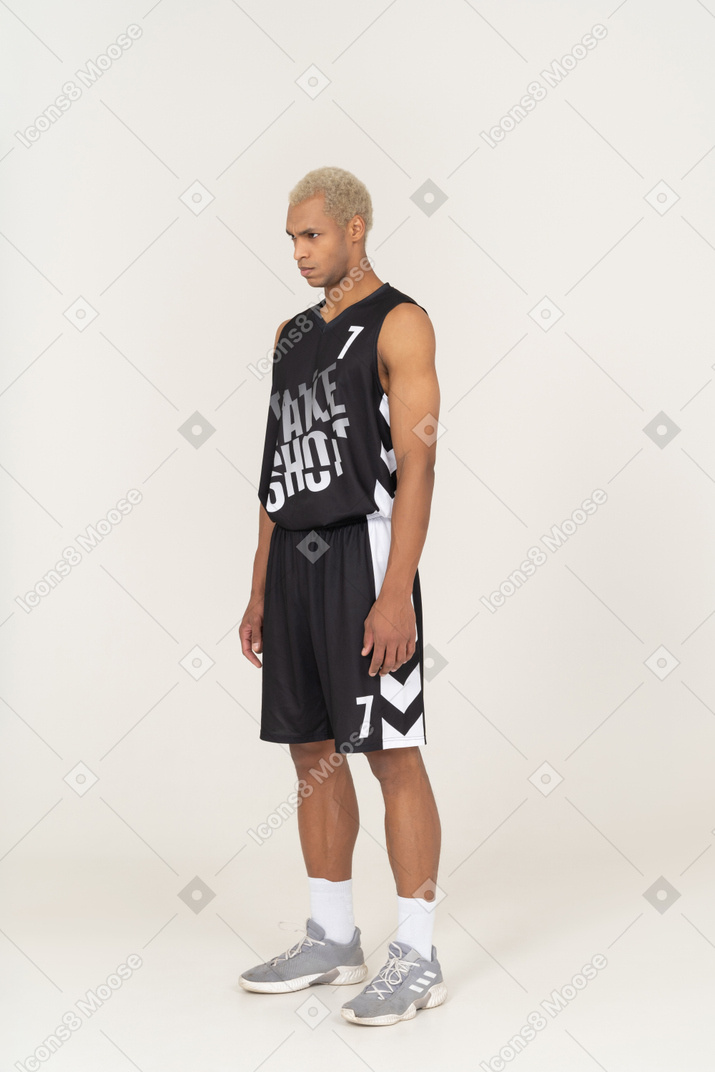 Vista de tres cuartos de un joven jugador de baloncesto masculino de pie con la cabeza hacia abajo