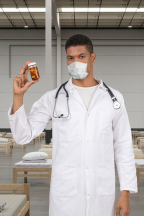 Man in a white lab coat showing jar of pills