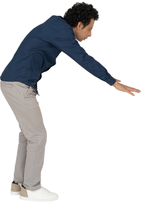 Side view of a man in casual clothes bending down with outstretched arms