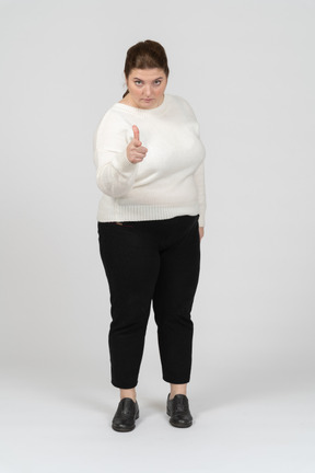 Front view of plump woman in casual clothes pointing with a finger