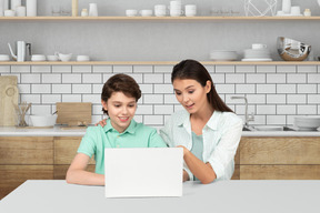 A woman and a boy are looking at a laptop