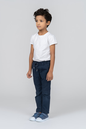 A boy standing with hands alongside body