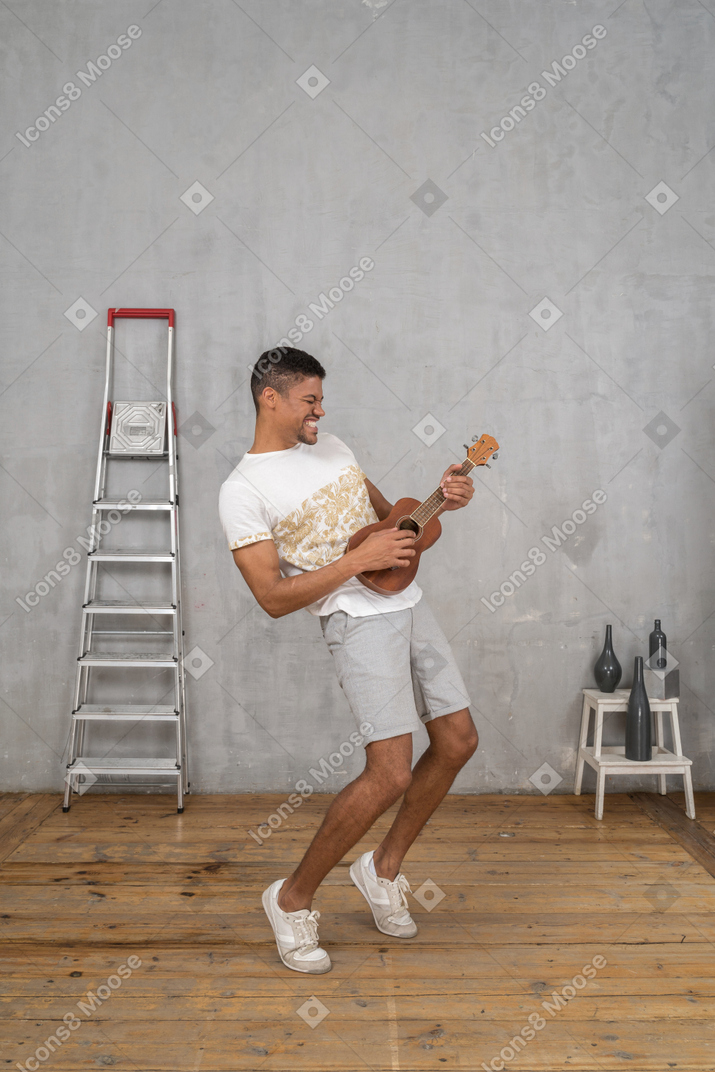 Dreiviertelansicht eines mannes, der auf einer ukulele rockt
