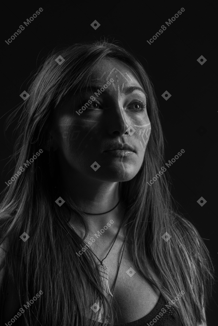 Three-quarter dark portrait of a young  hopeful woman with face art