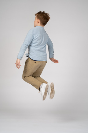 Back view of a boy in white sneakers jumping in the air