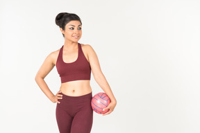 Молодая индийская женщина в спортивной одежде держит розовый шар