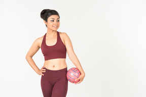 Junge indische frau in der sportkleidung, die rosa ball hält