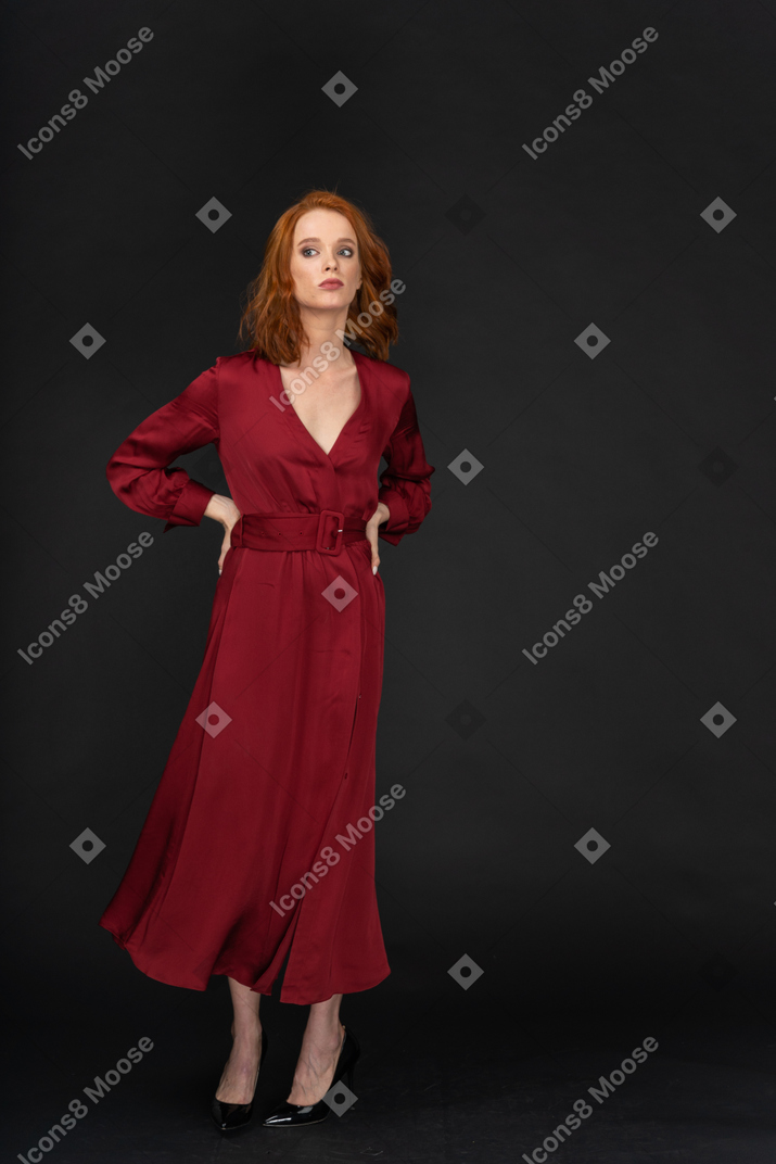 Giovane donna in abito rosso con le braccia sui fianchi