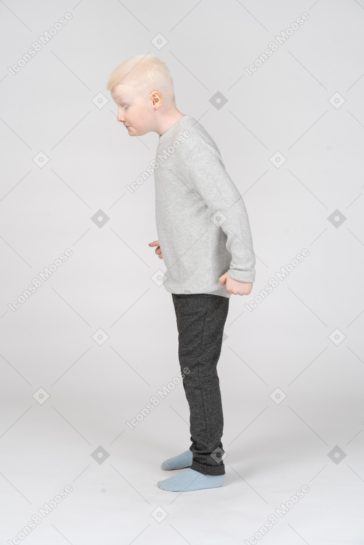 Side view of an angry little boy with clenched fists