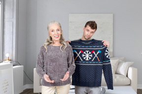 Elderly woman standing next to man holding christmas sweater