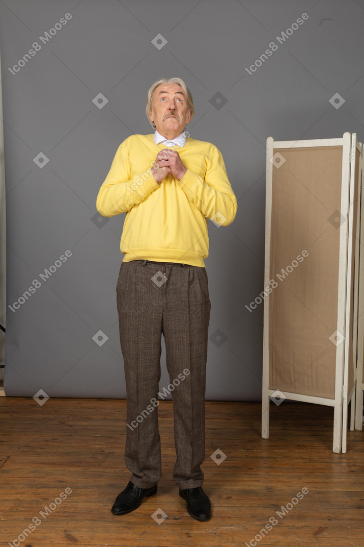 Front view of a surprised old man holding hands together