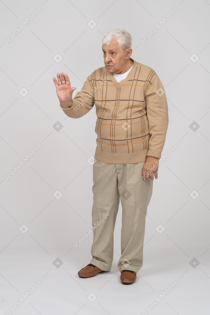 Vista frontale di un uomo anziano in abiti casual che mostra il gesto di arresto