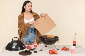 Jovem menina asiática tendo problema com churrasco