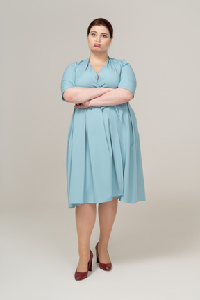 Vista frontale di una donna in abito blu in piedi con le braccia incrociate