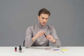 A young man using a black nail polish