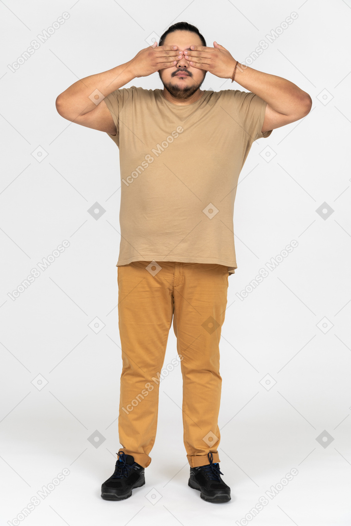 Plump asian man covering his eyes with both hands