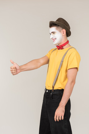 Happy male clown standing half sideways and showing thumb up