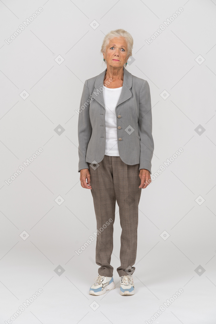 Vista frontale di una vecchia signora in abito che guarda la telecamera