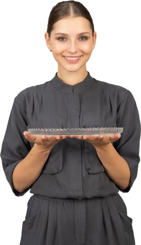 Front view of a young woman in a jumpsuit holding glass plate