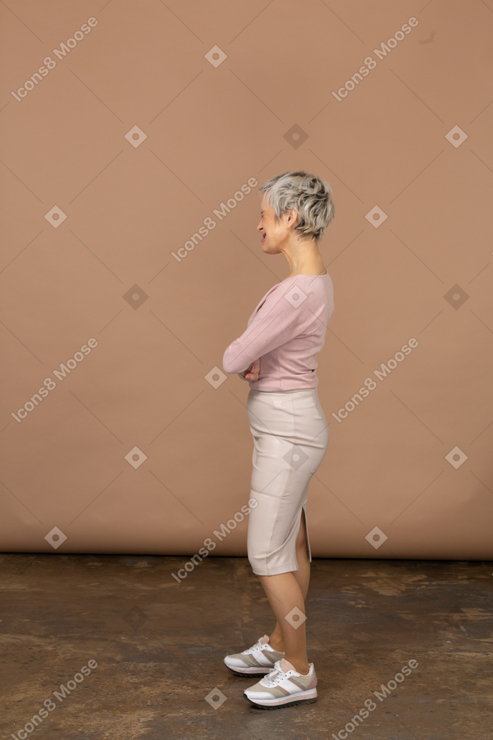 一个穿着休闲服的女人双臂交叉站立的侧视图