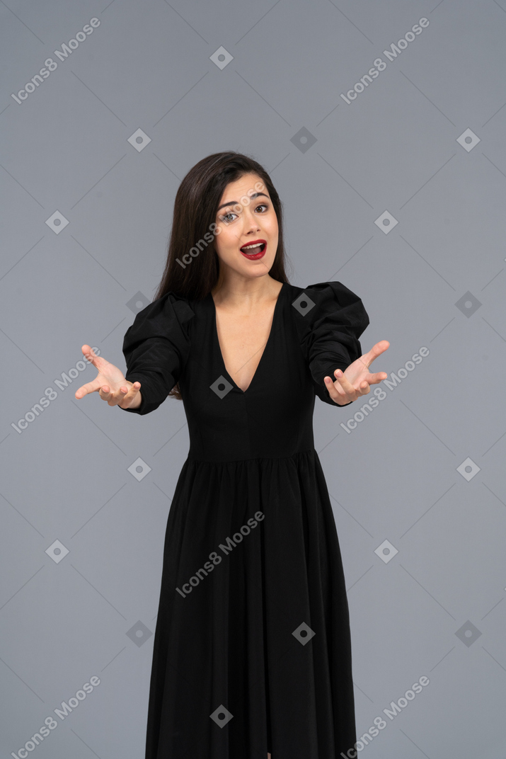 Vista frontal de uma jovem cantora em um vestido preto estendendo as mãos