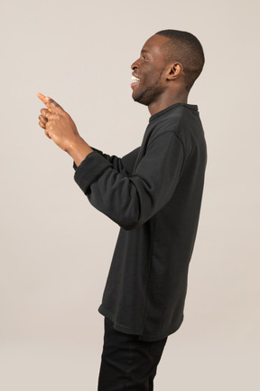 Seitenansicht eines jungen mannes, der lächelt und mit den zeigefingern zeigt
